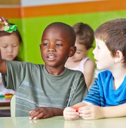 Children playing together, sat at desks
