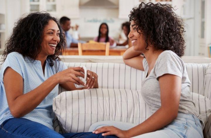 Two women sat on a sofa talking together
