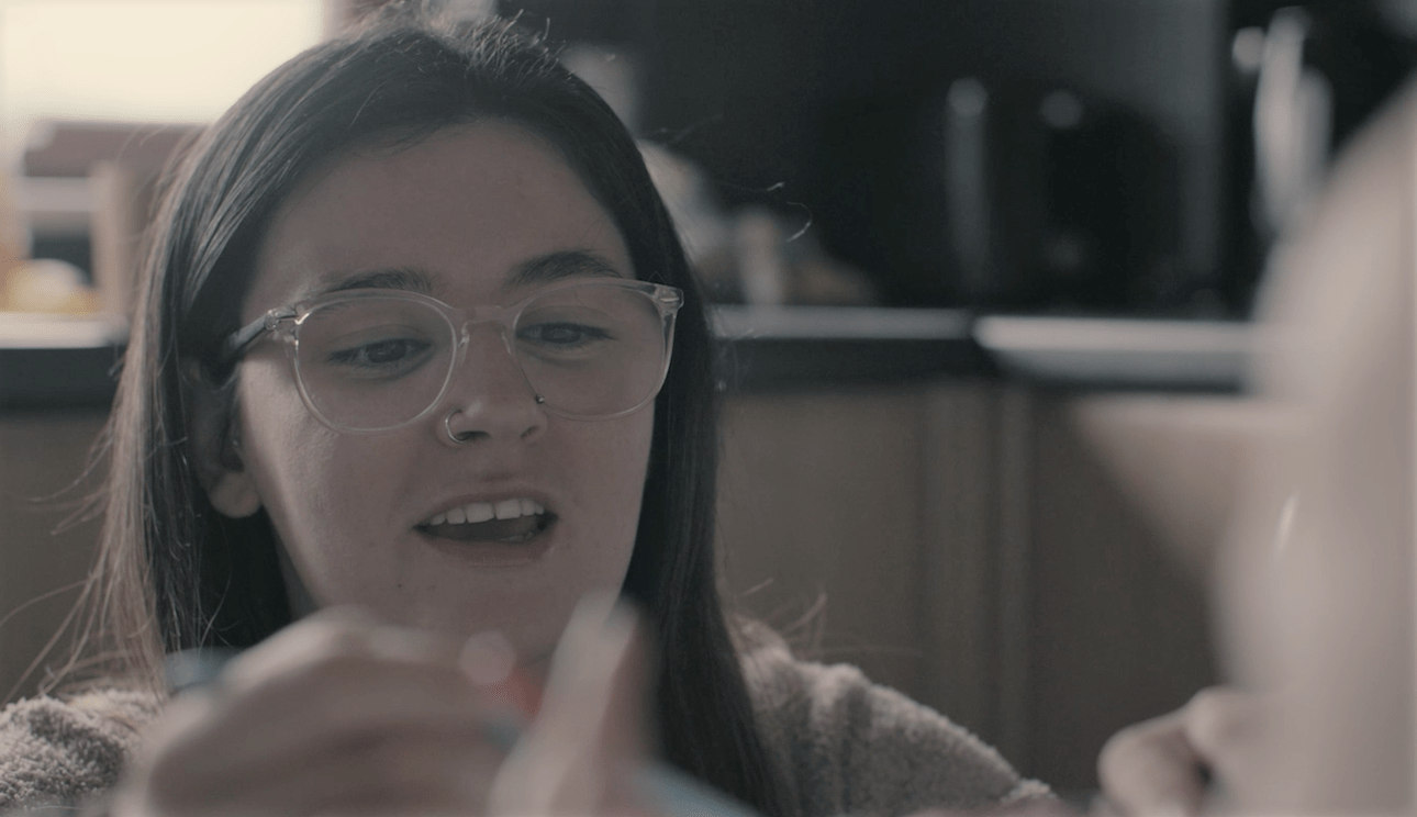 A woman wearing glasses, out of focus in the foreground is a baby